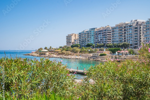 Exiles Bay Beach view through foliage and buildings in the background, Sliema MALTA