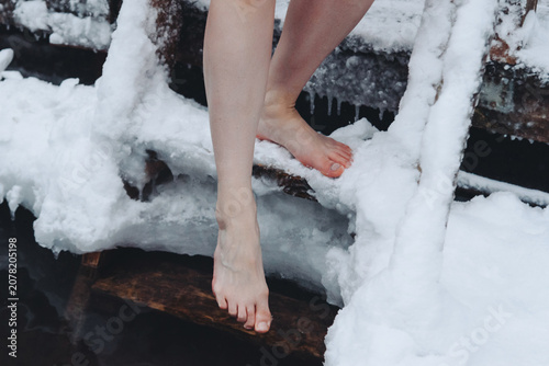 Foto close-up view of girl legs standing on wooden staircase, covered with snow and i