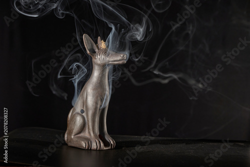 Anubis god statue with rising incense smoke