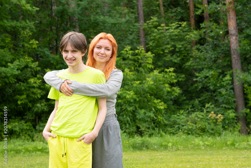Fototapeta premium Happy mother hugging her teenage son in summer forest