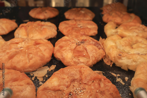 Golden brown savory pastries displayed in a bakery showcase, freshly baked and ready for sale.