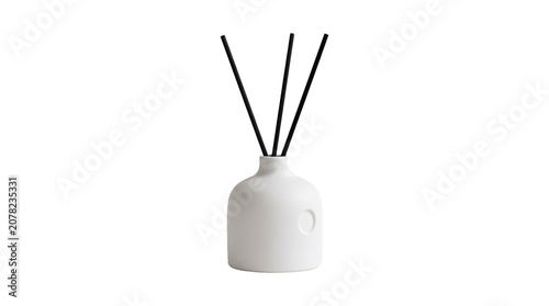 A white ceramic diffuser with three black sticks sits on a plain surface.