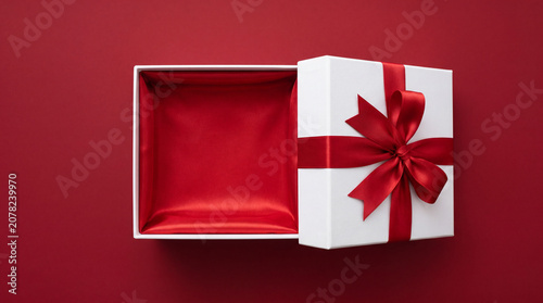 Top View Open White Gift Box with Red Satin Interior and Ribbon Bow on Red Background