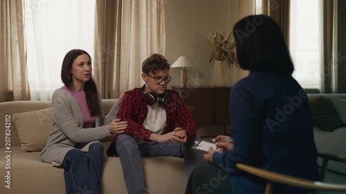 Worried mother and her adolescent son attending a teenage counseling session