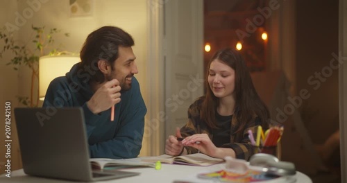 Smiling man and woman discussing notes at a laptop in a cozy home interior