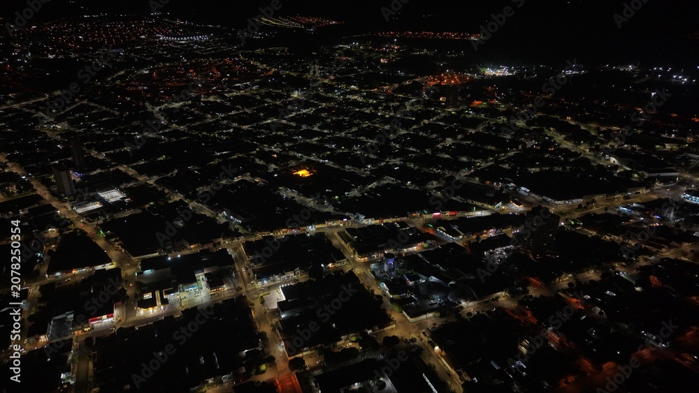 Fototapeta premium Aerial view of a city at night with illuminated streets and buildings creating a grid pattern