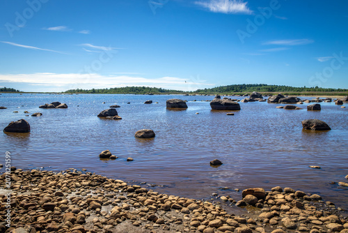 Rocky shore of Lake Ladoga with low water level and large boulders exposed on the dried beach in Karelia, Russia