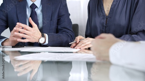 Business partners or lawyers are reviewing contract terms during a meeting, negotiating and making decisions together. Business people concept, close up view