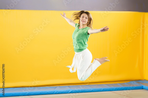 Foto Young woman jumping and bouncing on a trampoline in sport center