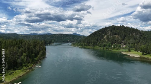 Aerial of Pend Oreille river flowing through forested valley near Ruby Washington with dense coniferous forest lining the banks and boat docks