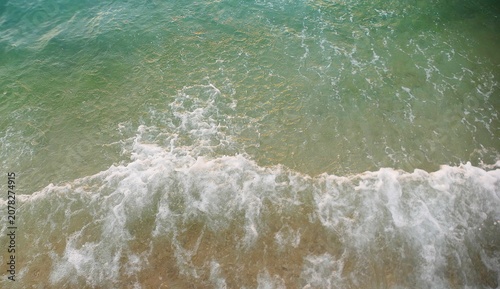 Fotografie Turquoise sea surface with crushing waves and foam colorful water ariel shot sum