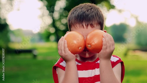 Small kid play juicy oranges. Child with grapefruit in hands close-up. Portrait little boy hold ripe oranges in hands. Healthy fruits from summer garden. Healthy happy child. Concept healthy lifestyle