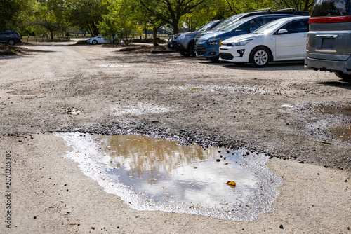 Foto Pothole with water puddle in a deteriorating gravel car park in Australia