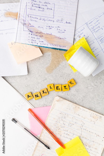 Concept of workplace stress,information overload, mental health, overwhelming workload, organization, and productivity challenges, Top view of handwritten notes, wooden letter spelling anxiety