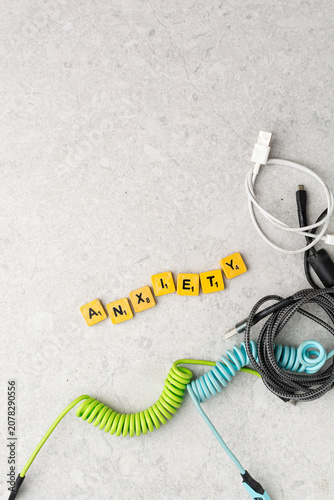Top view of assorted charging cables surrounding wooden letter tiles spelling 