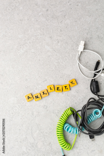 Top view of assorted charging cables surrounding wooden letter tiles spelling 