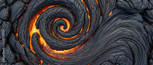 A close-up aerial view of a volcanic lava spiral glowing with intense orange heat surrounded by dark, cooled lava textures.