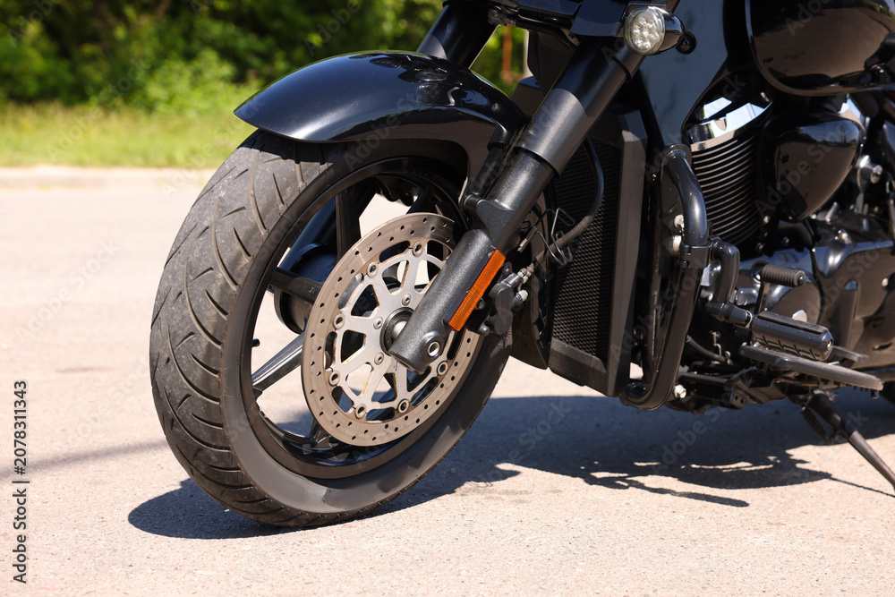 Obraz premium Modern black motorcycle parked on road outdoors, closeup