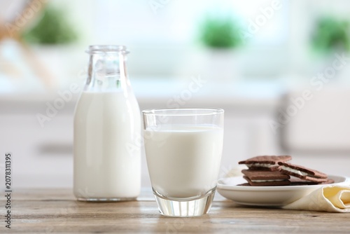 Photos Fresh milk and chocolate sandwich cookies on wooden table in kitchen