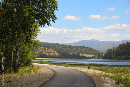 Sunny summer day view of the Trail of the Coeur d’Alenes beside wetlands and distant mountains near Harrison, Idaho.