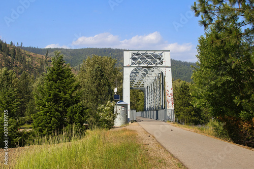 The view on a sunny summer day approaching on old railroad trestle along the Trail of the Coeur d’Alenes in the forest near Kellogg, Idaho.