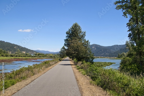 Sunny summer day view of the Trail of the Coeur d’Alenes passing between ponds in a mountain forest near Harrison, Idaho.