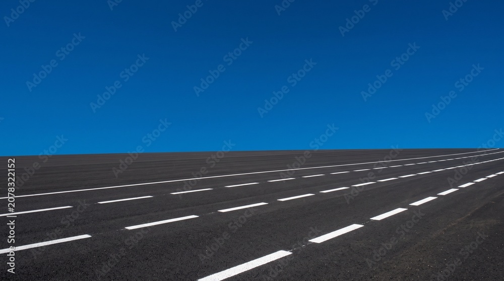 Fototapeta premium Empty Asphalt Road with White Lines Under a Clear Blue Sky