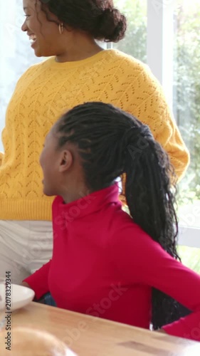 Vertical video: Bringing plate mother in yellow knit moving to child in red top at table serving