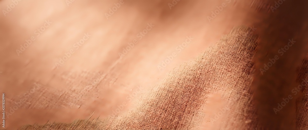 Fototapeta premium Close-up of warm copper-toned fabric with soft natural lighting, showcasing textile weave and material texture for design and fashion projects.