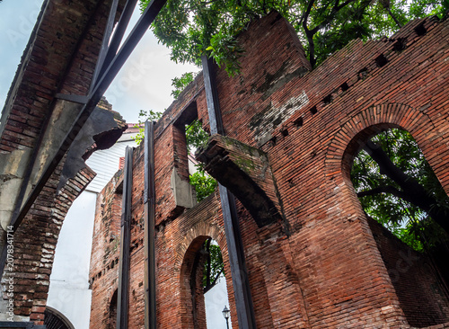 Fotografie The remnants of a historical brick structure, entwined with lush greenery
