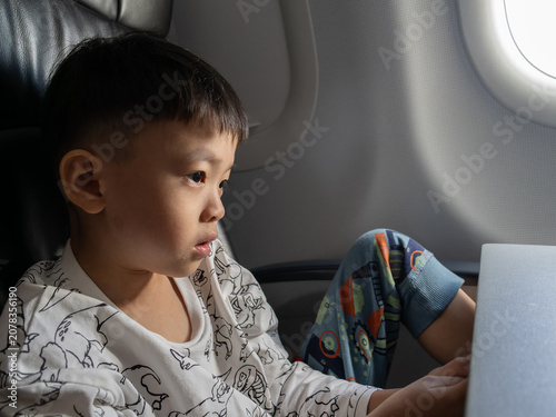 Konstfotografi Young boy engrossed in a smartphone while seated on an airplane.