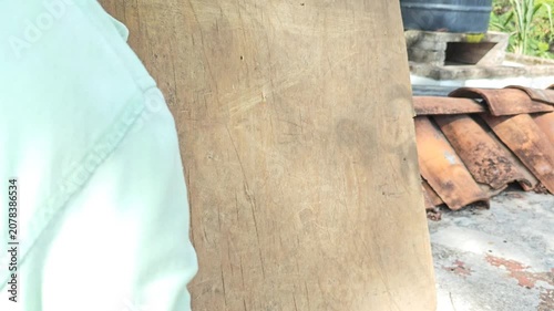 Hand using a wire brush to clean and texture a piece of wood lumber