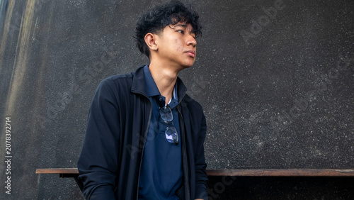 Foto young man wearing black jacket sitting against black wall
