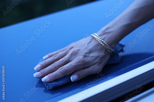 Main de femme nettoyant le rebord d’une fenêtre avec un chiffon
