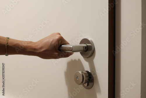 Main de femme saisissant une poignée de porte métallique