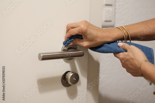 Femme nettoyant une poignée de porte avec un chiffon en microfibre