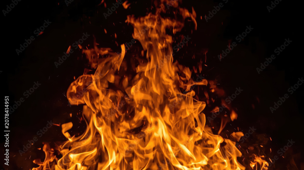 Fototapeta premium Vibrant orange flame rising from dark background with glowing sparks and dynamic motion