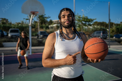 Foto Young man holding basketball pointing at opponent on court