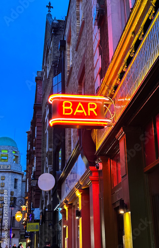 Red Neon Bar Sign Glowing Against Blue Twilight City Street
