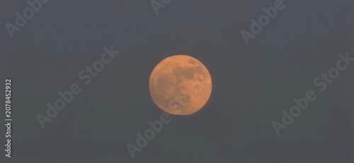 Valokuva Glowing harvest moon in a dark twilight sky, orange full moon rising at dusk, at