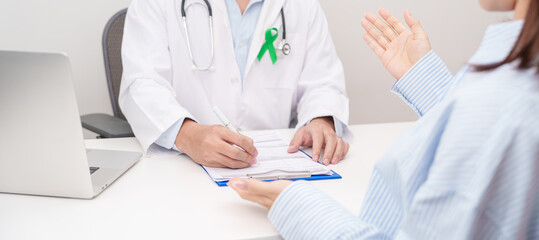 Doctor and patient having a medical consultation for lime Green Ribbon for concept of May Celiac Awareness month, Lyme disease, September Lymphoma, Mental Health Awareness month and Liver cancer