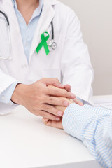 doctor holding patient hand to comfort and support with empathy. lime Green Ribbon for concept of May Celiac Awareness month, Lyme disease, September Lymphoma, Mental Health and Liver cancer