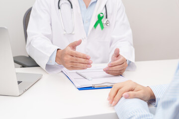 Doctor and patient having a medical consultation for lime Green Ribbon for concept of May Celiac Awareness month, Lyme disease, September Lymphoma, Mental Health Awareness month and Liver cancer