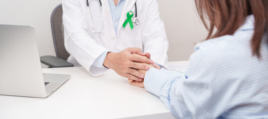 doctor holding patient hand to comfort and support with empathy. lime Green Ribbon for concept of May Celiac Awareness month, Lyme disease, September Lymphoma, Mental Health and Liver cancer