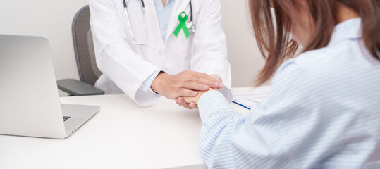 doctor holding patient hand to comfort and support with empathy. lime Green Ribbon for concept of May Celiac Awareness month, Lyme disease, September Lymphoma, Mental Health and Liver cancer