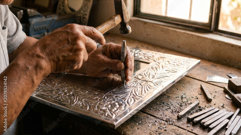 Obraz premium Mexican tinsmith hand punching decorative mirror frame steel stamp San Miguel workshop photo