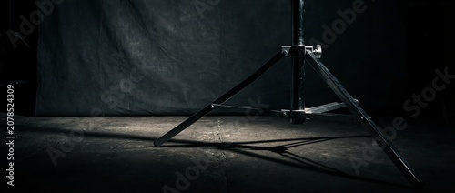 Dark studio backdrop with tripod and dramatic lighting shadows