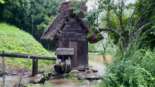 Traditional Japanese shishi-odoshi bamboo water feature operating on a rainy day in Shirakawa-go, Japan