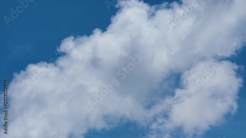 A large, fluffy white cloud drifting slowly across a vibrant blue sky with gentle motion.