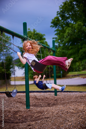 Laughing Little Girl Enjoying Playground Swing on Summer Day - Active Outdoor Play